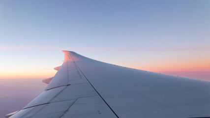 Fototapeta na wymiar Airplane wing and colorful sunrise sky background