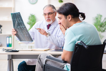 Obraz premium Male patient in wheel-chair visiting old doctor 