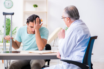 Obraz premium Young leg injured male patient visiting old doctor 