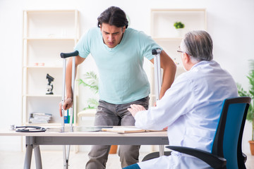 Obraz premium Young leg injured male patient visiting old doctor 