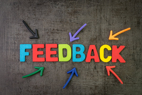 Customer feedback, review or rating concept, multi color arrows pointing to the word Feedback at the center of black cement chalkboard wall