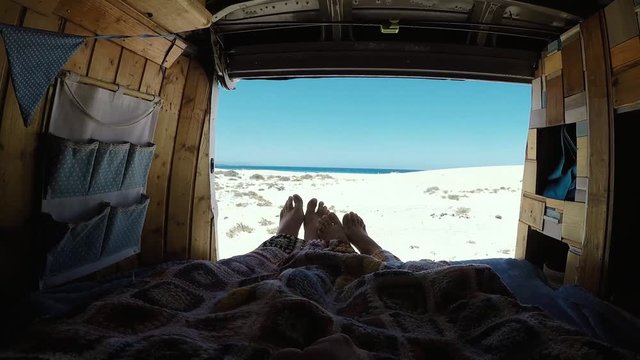 Romantic people inside old van for love concept and alternative lifestyle and vacation with vehicle camper - beach and ocean view luxury - enjoying nature and outdoors - wanderlust life