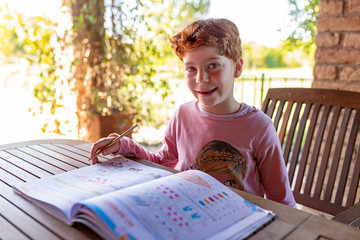 Bambina che legge e fa i compiti di scuola, sorridente in una giornata di vacanza