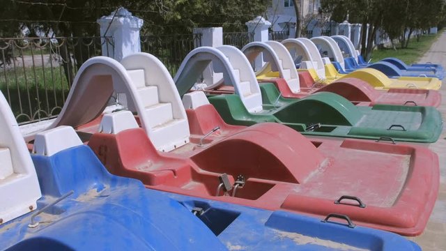 Colored catamarans on the waterfront near the sea along the fence. Catamaran rental for tourists. River and sea transport for recreation activity outdoor.