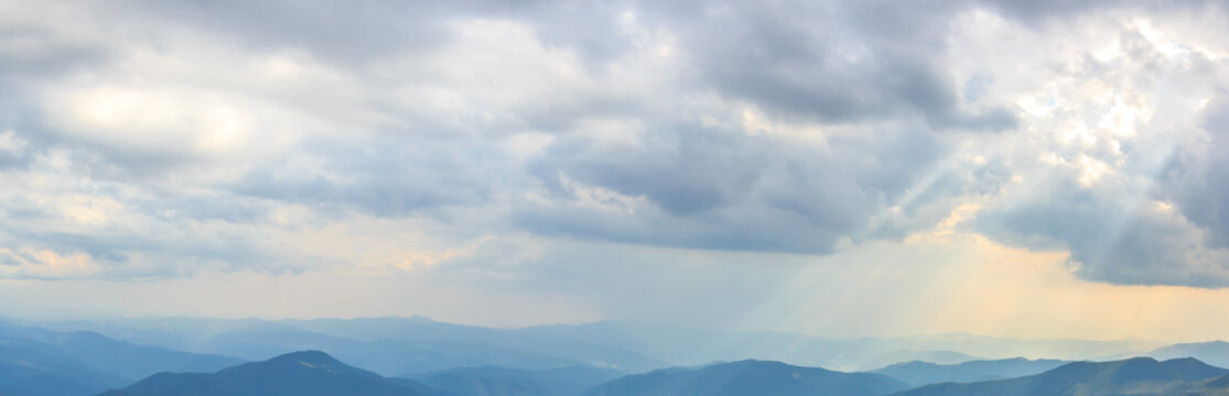 The sun's rays penetrating through the clouds on the surface of the mountains, panoramic view.
