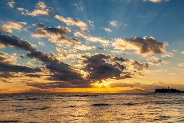 Fototapeta na wymiar 鎌倉稲村ケ崎から海に沈む夕日と雲間からこぼれる光芒