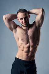 Muscular shirtless man posing with hands over head