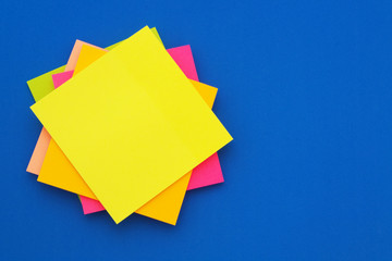 Colorful paper stickers on blue background, blank note papers with space for text.