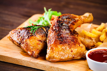 Roasted chicken leg with french fries and vegetable salad on wooden background