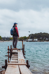 man standing at edge of the small fishing pier looking at stormy sea
