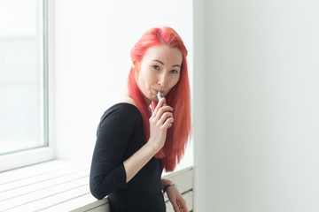 Vape, addiction and people concept - young woman with colored hair is smoking a vape