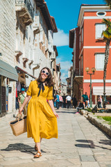 Fototapeta na wymiar tourist woman in yellow sundress walking by small croatian city street