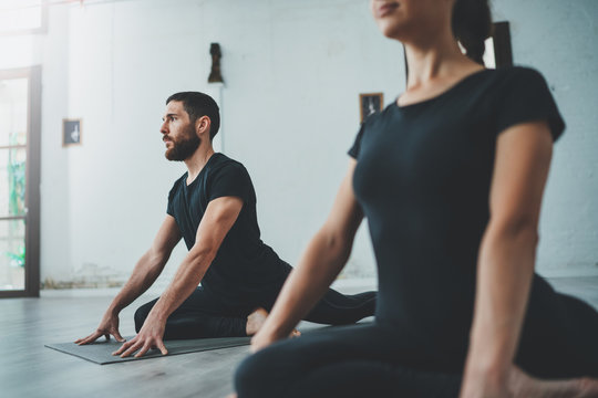 Yoga Practice Exercise Class Concept. Two beautiful people doing exercises.Young woman and man practicing yoga indoors