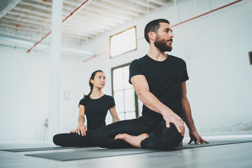 Yoga Practice Exercise Class Concept. Two beautiful people doing exercises.Young woman and man practicing yoga indoors