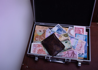 Colorful banknotes in silver suitcase.