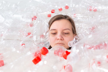 Dehydrated sick woman is lying in a pile of plastic bottles. Environmental pollution problem. Stop nature garbage environment protection concept