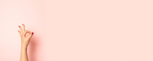 Close up photo of young woman hand showing OK gesture isolated on pink background