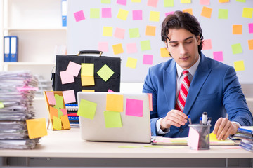 Young male handsome employee in conflicting priorities concept 