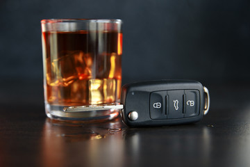 The concept of a DUI. Law hammer, alcohol and car keys on wooden table, dark background