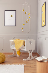 White wooden cradle with yellow cozy blanket in the middle of fashionable nursery