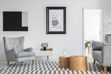 Fototapeta na wymiar Comfortable grey armchair in elegant living room interior with white furniture and two wooden coffee tables