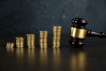 Close-up Of A Judge's Hand Holding Gavel Over Stacked Golden Coins