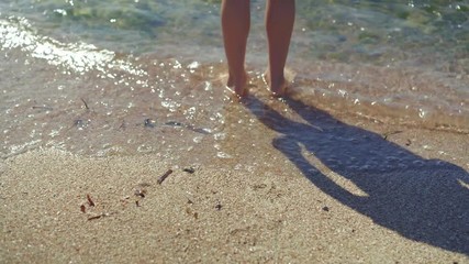 Barefoot child stand in the sea water enjoy the summer. Kid having fun outdoors.