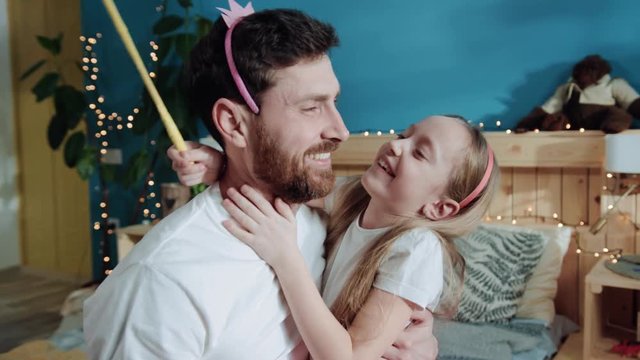 Father and daughter play fairytale dressed like fairies at home party. Closeup happy little girl kissing her daddy smiling broadly. Lovely portrait. Tenderness and love concept.