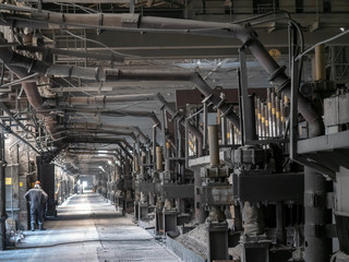 Modern large aluminum foundry with casting cells. Electrolytic bath with flame in opened door. Line is in long workshop.  Aluminium Smelter. Safe environmental high-tech processes. Modern smelter