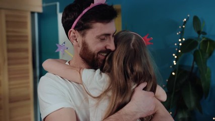 Happy family moments. Closeup affactionate young father huggins and kissing his little daughter playing together at birthday party.