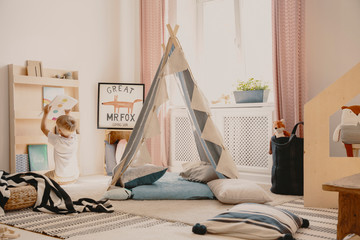 Pillows and carpets on the floor of cozy playroom of single kid, real photo