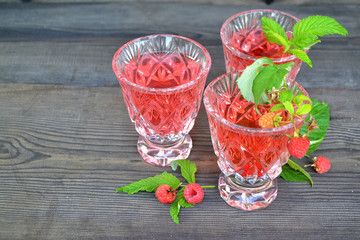 Summer fruit jelly in crystal bowl with fresh raspberries, on black wooden table. Diet healthy breakfast.
