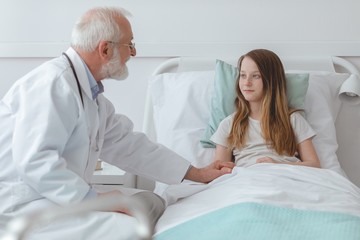 Obraz premium Doctor comforting a young girl in the hospital