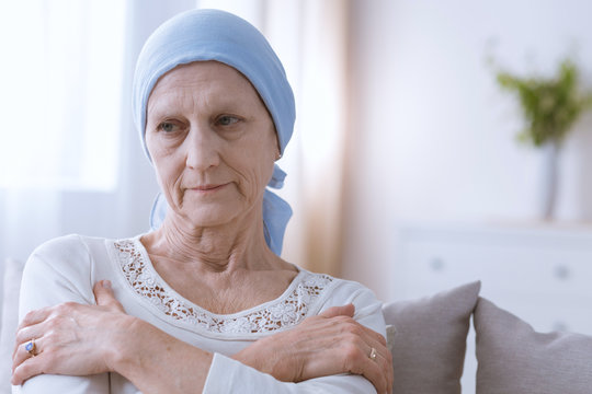 Senior sad woman wearing blue headscarf, suffering from hair loss after cancer treatment