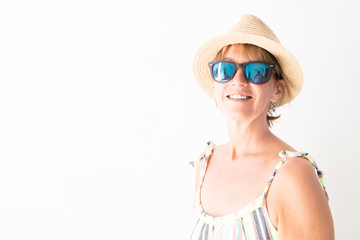 A high contrast white bleached effect photo of a lady in summery clothing against a white background.She wears sunglasses and a hat - Image