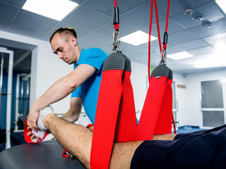 Physiotherapy. Suspension training therapy. Young man doing fitness traction therapy with...