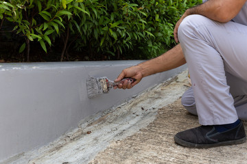 Man worker painting concrete wall with paintbrush.