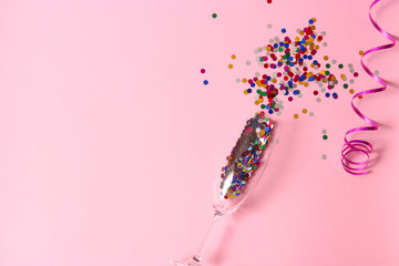 glasses and confetti on a colored background top view.