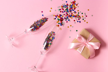 glasses and confetti on a colored background top view.