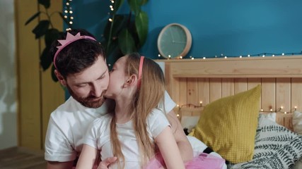 Cute family hugs. Closeup cheerful pleasant father holding his princess sweet daughter kissing together. Portrait of smiling daddy and little girl child at home.