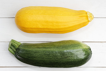 Closeup fresh raw yellow and green zucchini on white wooden table. Top view.