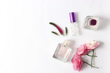 A beautiful arrangement of flowers and perfumes on a light background top view