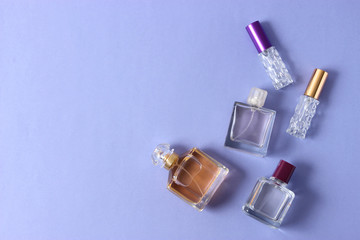 set of different perfumes on a colored background top view.