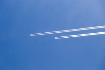 Two passenger aircraft flying nearby. Condensation trail from an airplane in a blue sky.