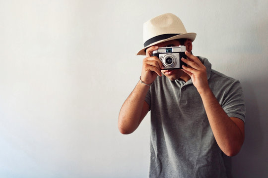 Man dressed in gray and in a hat taking some pictures with his camera.
