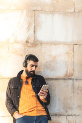 Young Hipster Man Using Cell Phone and Listening Music .