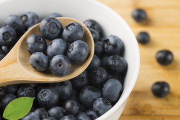 Fresh picked blueberries on white bowl, healthy summer snack on wooden table