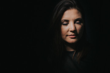 Naklejka premium Low key studio portrait of women in her thirties with eyes closed