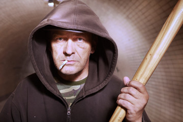 Older addict man in black hooded shirt with weapon