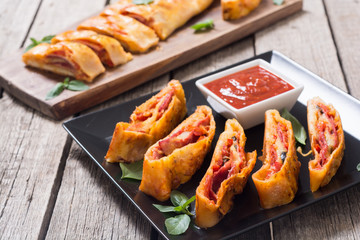 Pizza roll stromboli with cheese salami olives and tomatoes
